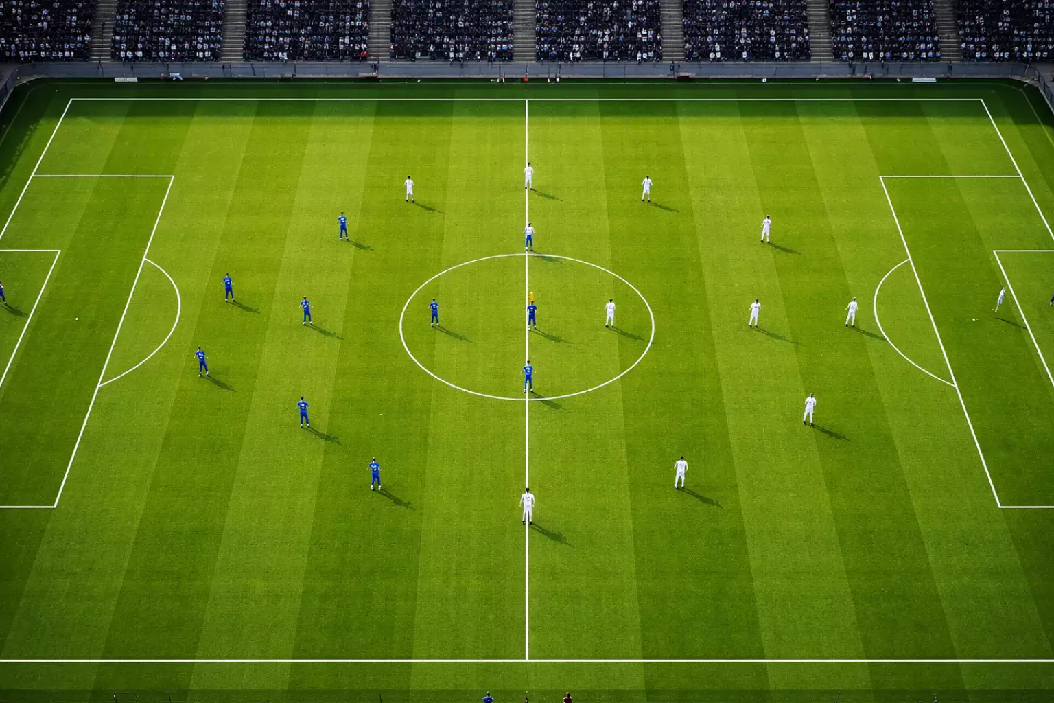 Campo di calcio visto dall'alto con le due squadre schierate in formazione